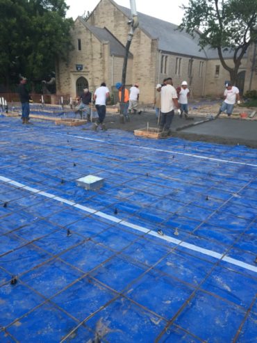 Rebar is laid out to reinforce the concrete slab being poured. Construction workers vibrate the concrete to eliminate any air bubbles before smoothing it out.